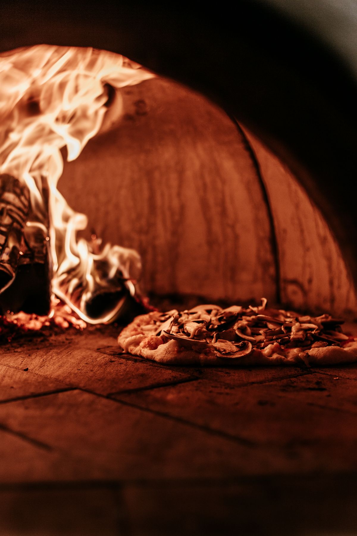 Pizza cuisant dans un four à bois, flammes visibles