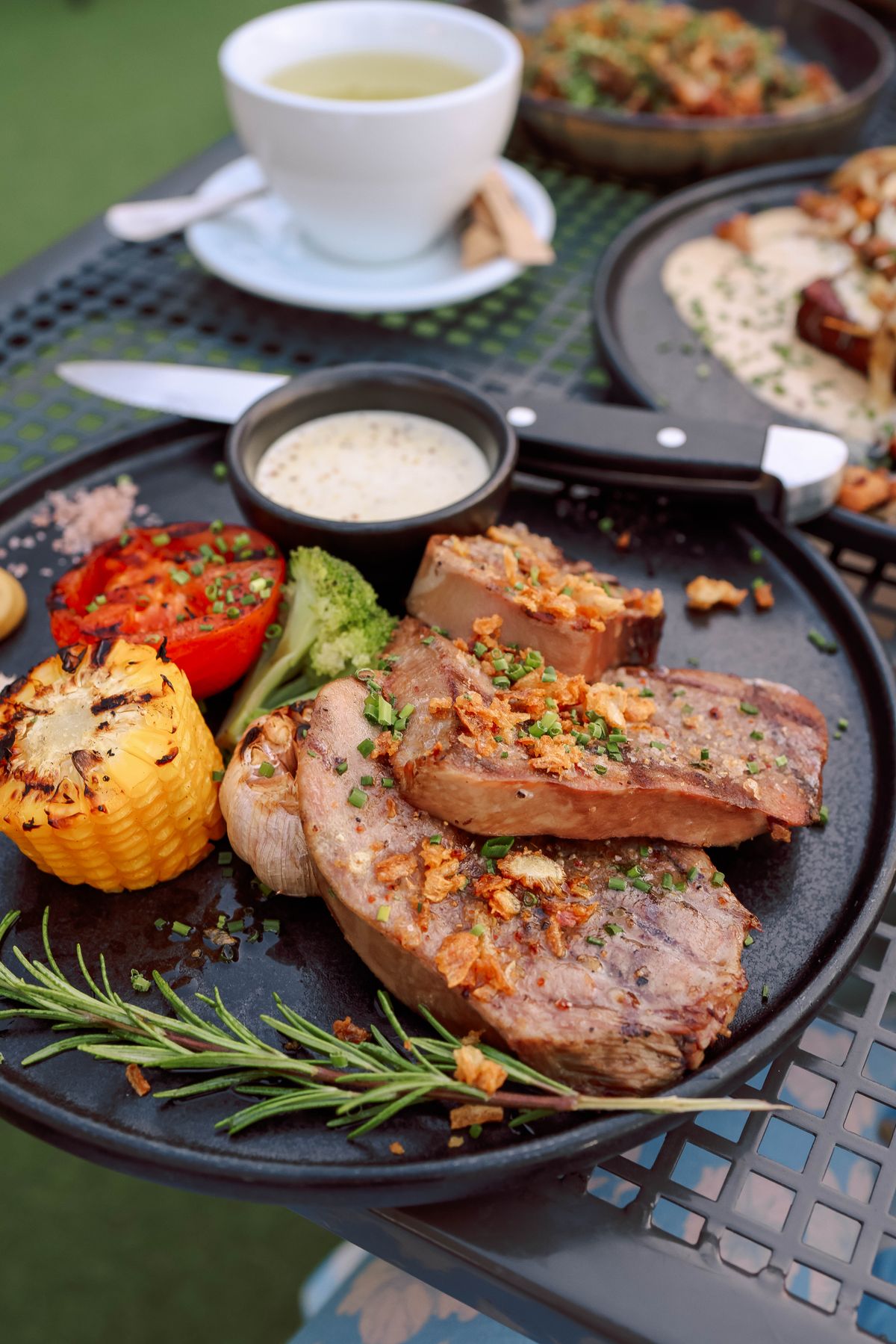 Viande grillée dressée avec des légumes rôtis et des herbes