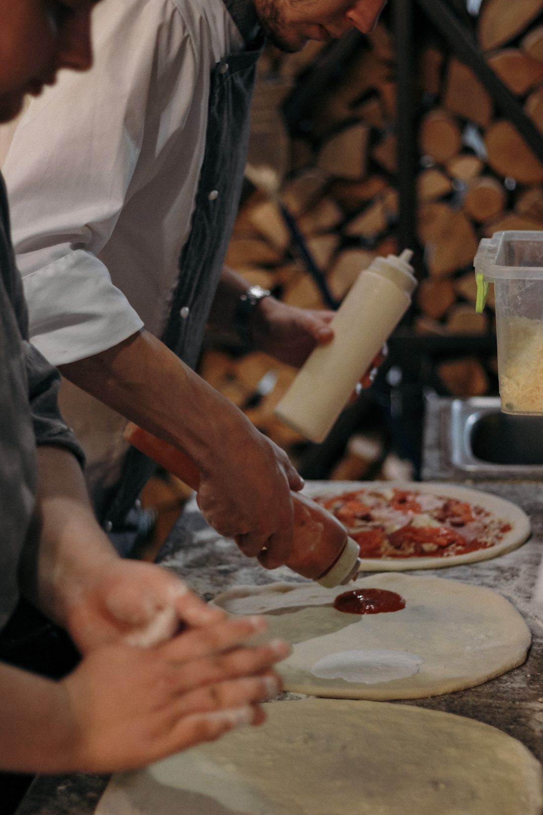 Des mains pétrissent et étalent une pâte à pizza sur un plan fariné