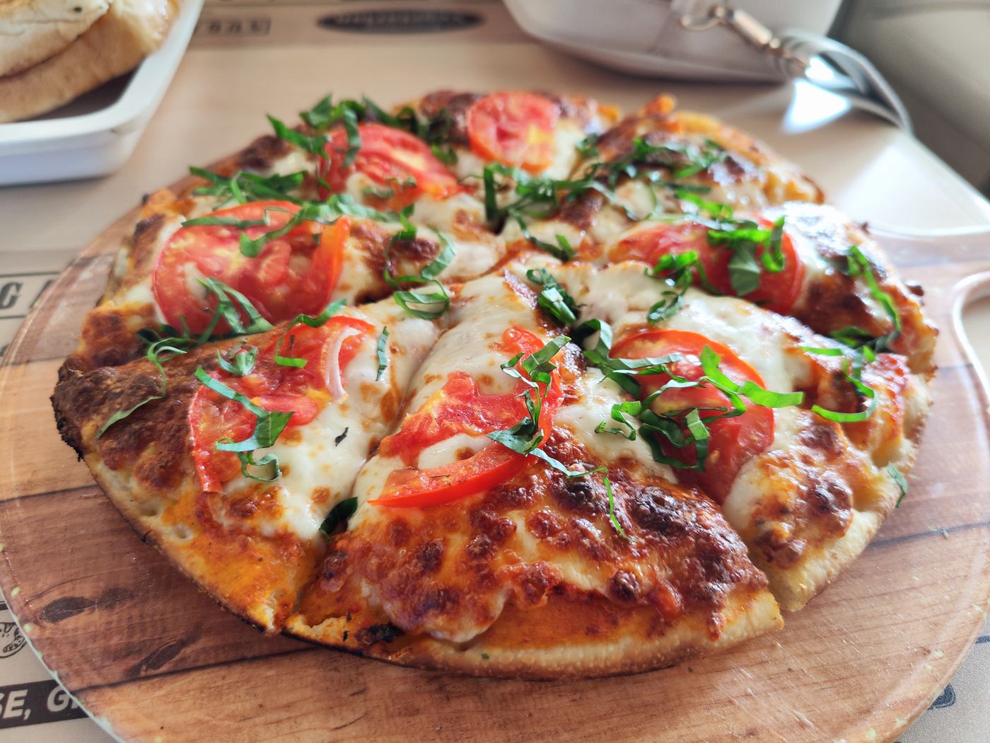 Pizza aux tomates fraîches et au basilic, servie sur une planche en bois